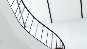 Eine Wendeltreppe mit schwarzer Geländer, weißen Wänden und einem Holzhandlauf.