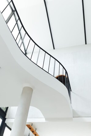 Eine Wendeltreppe mit schwarzer Geländer, weißen Wänden und einem Holzhandlauf.