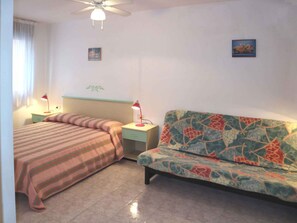 A bedroom with a bed, a sofa, two bedside tables with lamps, a ceiling fan, and two wall-mounted pictures. - Holiday apartment mit Klimaanlage und Garten (Lignano Sabbiadoro)