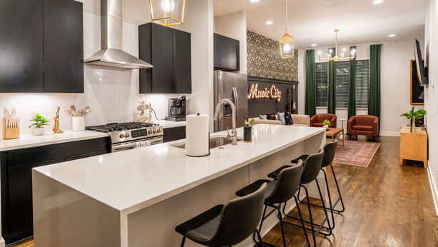 A modern kitchen with a central island, bar stools, a large stove, and a stainless steel range hood. - The Bluebell - Music City Views, Game Room, 11 Beds! (Nashville)