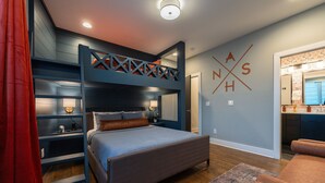 A bedroom with a bunk bed, a desk, and a bathroom visible through an open door. - The Bluebell - Music City Views, Game Room, 11 Beds! (Nashville)