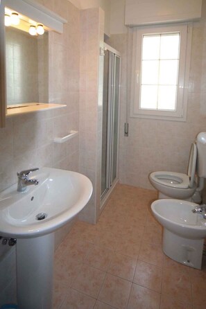 Een badkamer met twee wastafels, een toilet, een douche en een raam.