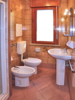 Ein Badezimmer mit zwei Toiletten, einem Bidet und einem Waschbecken.