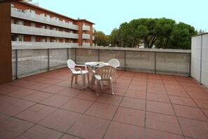 Een dakterras met een tafel en stoelen, omgeven door een metalen hek.