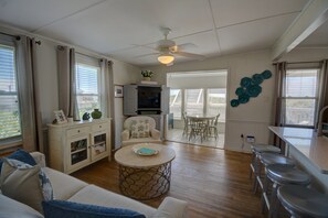 A living room with a sofa, a coffee table, a TV, and a dining area with a table and chairs. - Cozy 2BR retreat in North Topsail Beach, perfect for relaxing getaways (North Topsail Beach)