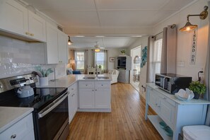 A kitchen with white cabinets, a black stove, and a microwave on a white countertop. - Cozy 2BR retreat in North Topsail Beach, perfect for relaxing getaways (North Topsail Beach)