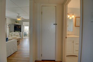 Ein Flur mit einer weißen Tür, einem Deckenventilator, einem Fernseher und einem Essbereich mit Tisch und Stühlen.