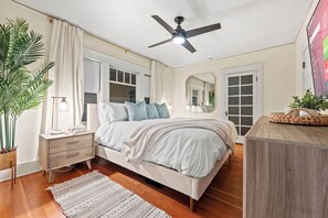 Une chambre à coucher avec un lit, une table de chevet, une lampe et un ventilateur de plafond.