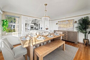 A modern kitchen with a dining area, large windows, and a chandelier. - Prestigious Hills Estate | Stunning Pool & Hot Tub Views (San Diego)