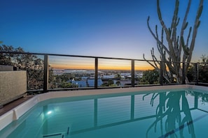 A swimming pool with a view of a cityscape at sunset. - Prestigious Hills Estate | Stunning Pool & Hot Tub Views (San Diego)
