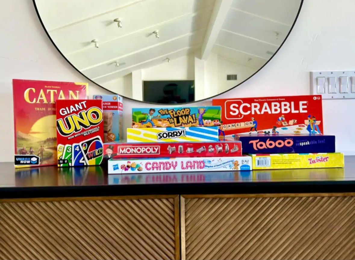 A variety of board games on a table, including Catan, Monopoly, and Scrabble.