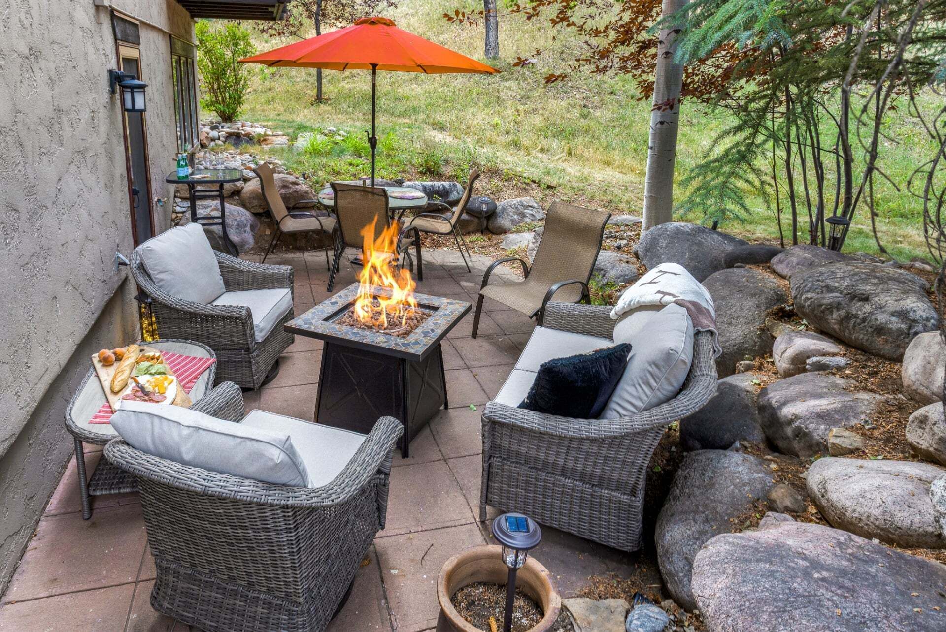 An outdoor patio with wicker furniture, a fire pit, and a dining table with food.