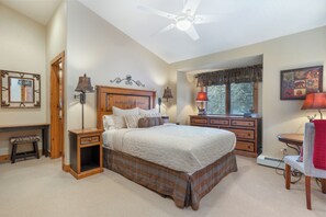 Une chambre à coucher avec un grand lit, des tables de chevet en bois, un bureau et une chaise.