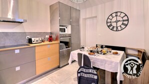Een moderne keuken met een inbouwoven, magnetron en broodrooster. Er staat een ontbijttafel gedekt.