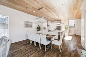 A modern kitchen with white cabinets, a wooden ceiling, and a dining area with a table and chairs. - Eastern Lake w/ Private Pool, Hot Tub, LSV/Golf Cart, Bikes! Walk to Beach! (Santa Rosa Beach)