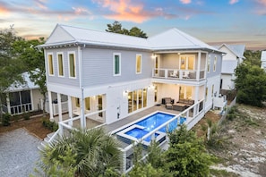 Ein zweistöckiges Haus mit Pool, Balkon und überdachter Terrasse.