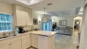 Una cocina amplia con lavavajillas, ventilador de techo y zona de comedor con sofá.