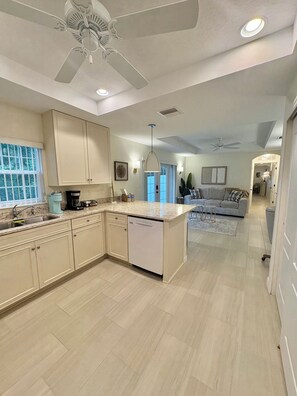 A spacious kitchen with a dishwasher, a ceiling fan, and a dining area with a couch.