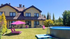 A two-story house with a swimming pool, a patio with chairs and an umbrella, and a well-maintained lawn. - 1 bedroom lovely apartment in Rowy (Rowy)