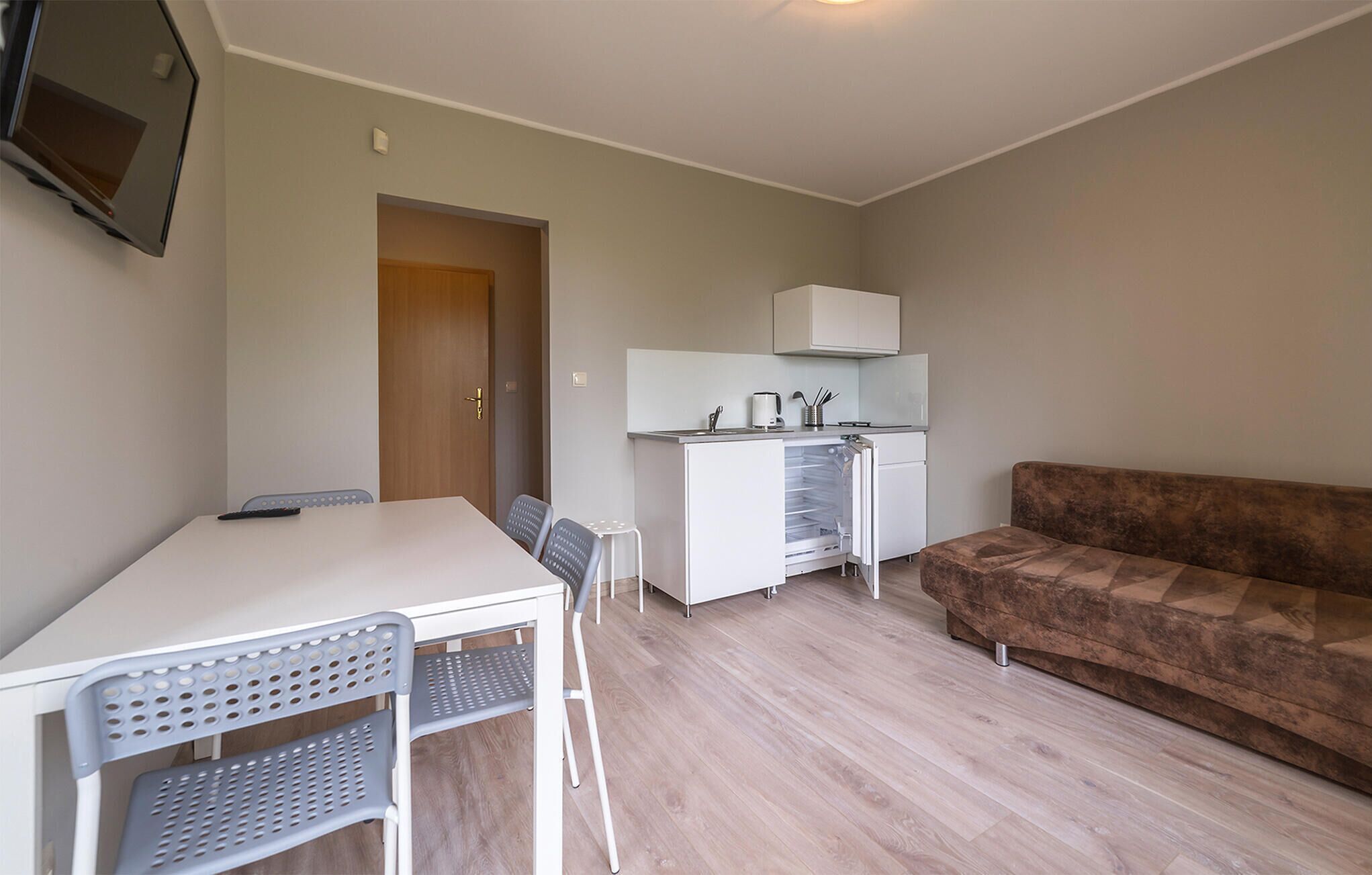A compact living space with a kitchenette, a dining area with a table and chairs, and a sofa.