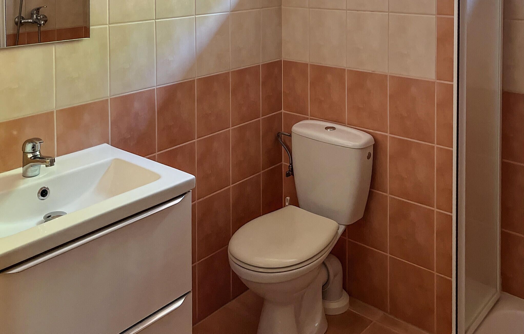 Un baño con lavamanos, inodoro y ducha blancos.