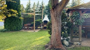A backyard with a stone barbecue, wooden pergola, and a gazebo. - 1 bedroom lovely apartment in Rowy (Rowy)