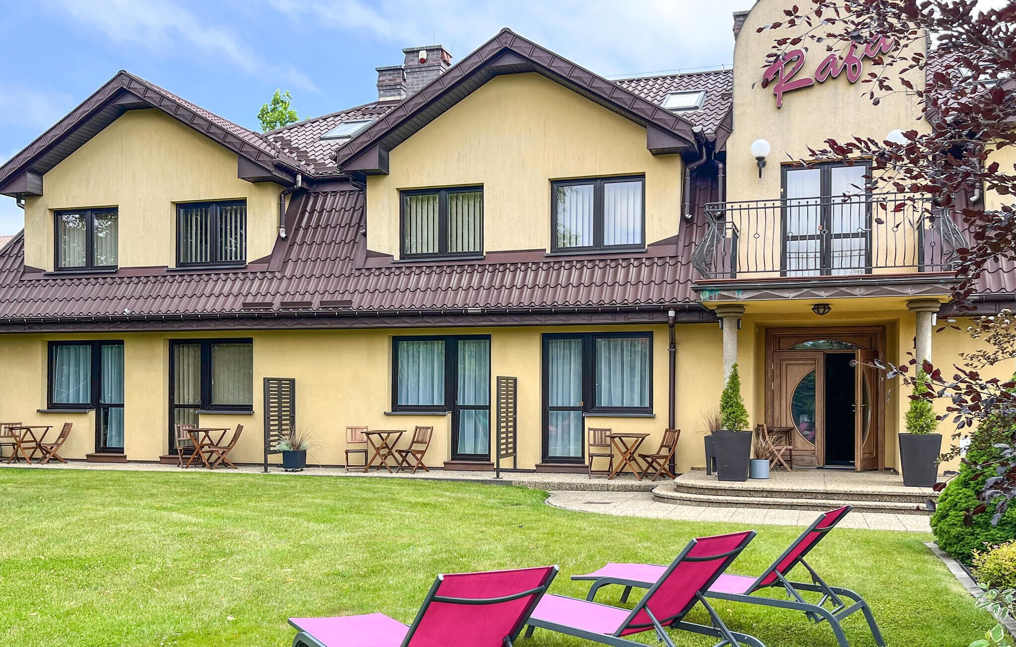 Ein zweistöckiges Gebäude mit gelber Fassade, zahlreichen Fenstern und einem Balkon.