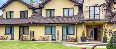 Ein zweistöckiges Gebäude mit gelber Fassade, zahlreichen Fenstern und einem Balkon.