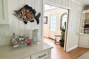 Cucina con piano di lavoro bianco, macchina da caffè e decorazione a tema pesci.