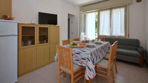 Un espacio habitable pequeño con zona de comedor, kitchenette y sofá.