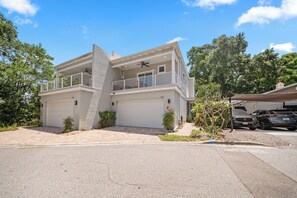 A two-story house with a garage, a balcony, and a small garden area. - Modern Dunedin Home - Walk to Downtown, Near Beach (Dunedin)