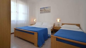 A double room with two single beds, each with a blue bedspread and white pillows. There is a painting on the wall above the beds, and two bedside lamps. - Holiday flat with air conditioning and balcony (Lignano)