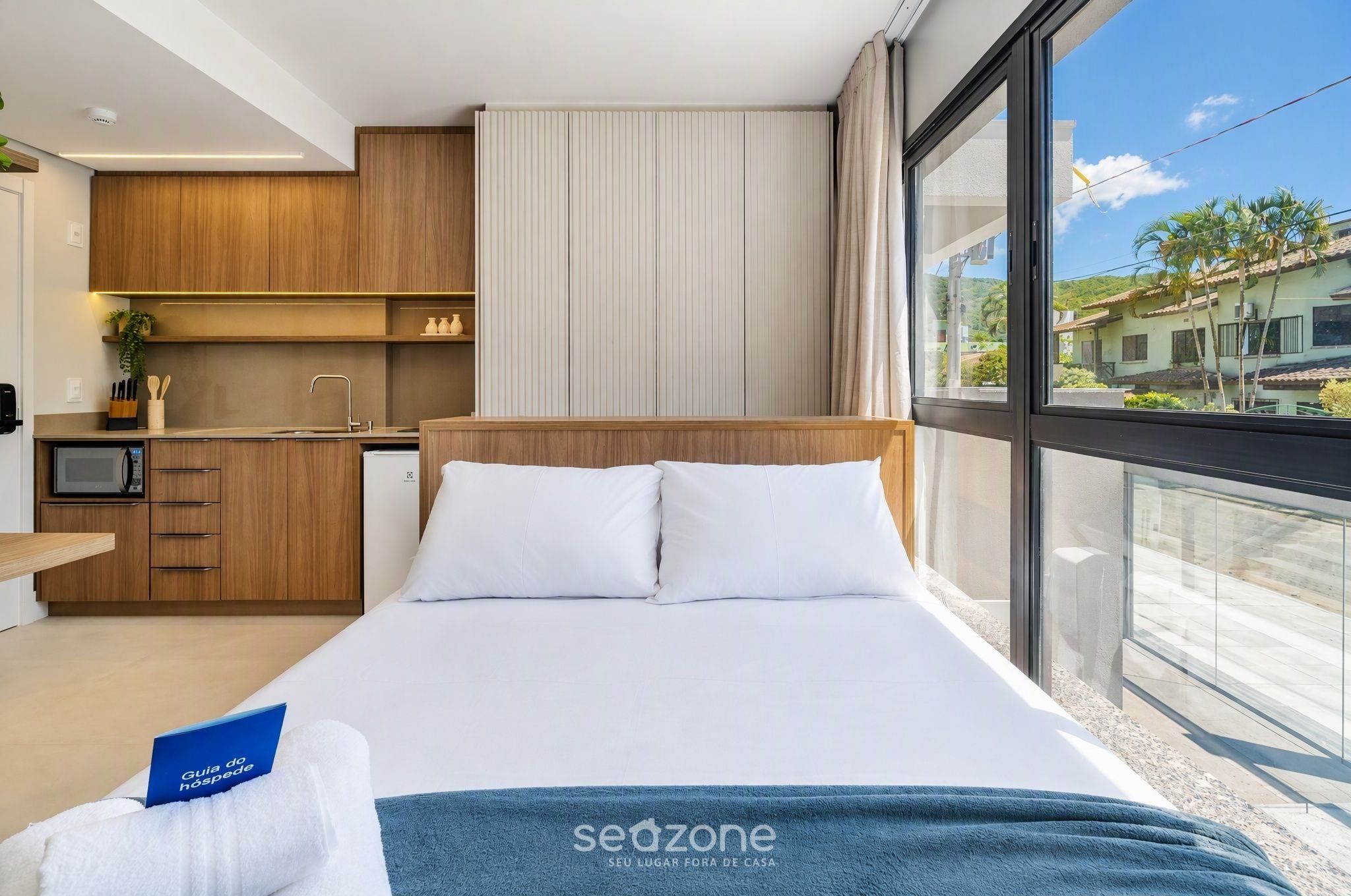 Una camera d'albergo moderna con un letto, angolo cottura e un balcone con vista.