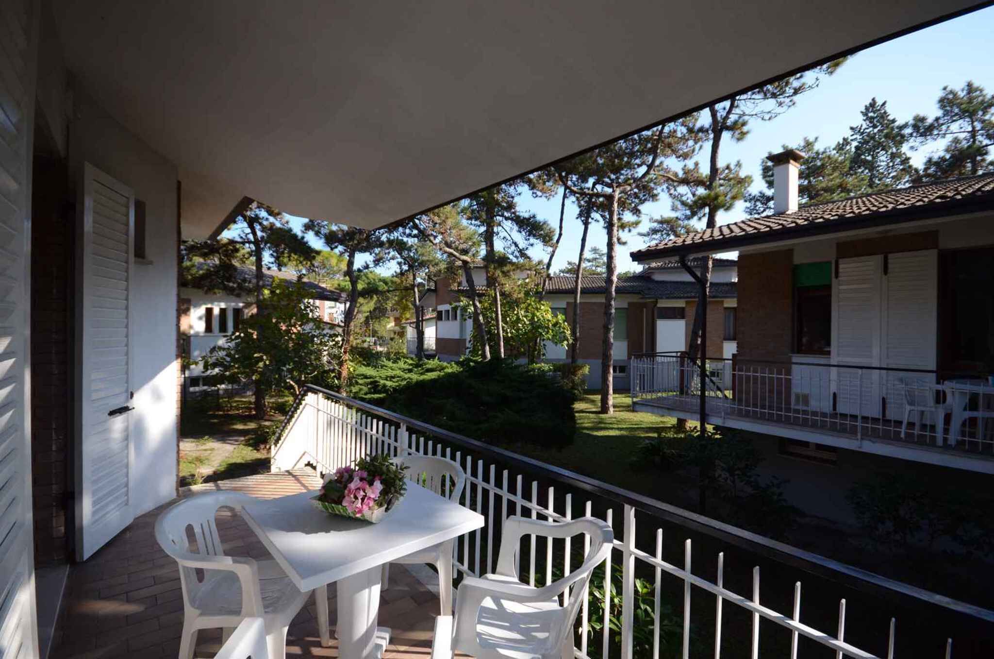 A balcony with a table and chairs, overlooking a residential area with houses and trees.