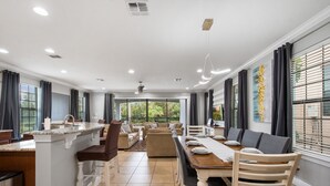 Un vaste espace de vie comprenant une table à manger, des canapés et un îlot de cuisine.