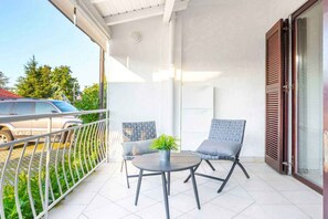 En balkon med to stole, et lille bord og en potteplante.