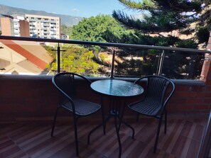 Ein Balkon mit zwei Korbstühlen und einem kleinen runden Tisch.