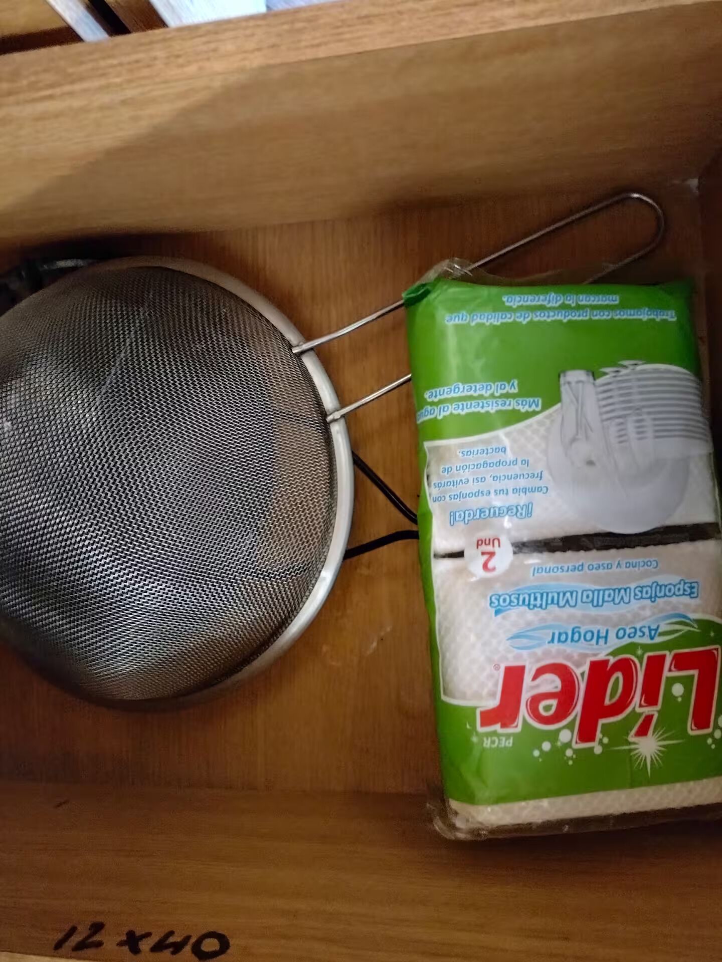 A wooden drawer containing a mesh strainer and a green package of L'ile de Paris.