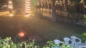 A well-lit outdoor area with a fire feature, seating, and decorative lights. - Luxury 2BHK Villa with Private Pool – Sector 135, Noida (Noida)