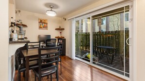 A dining area with a table and chairs, a television, and a kitchen counter with appliances. - Cozy Work-ready 1BR Condo Near Downtown (Bellevue)