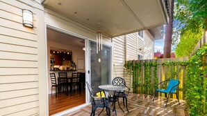 An outdoor patio with a wooden floor, a table with chairs, and a blue chair. - Cozy Work-ready 1BR Condo Near Downtown (Bellevue)