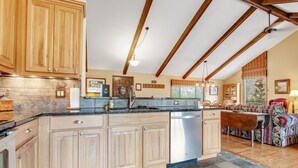 A spacious kitchen with wooden cabinets, a large island, and a dining area with a patterned sofa. - 3BR with Epic Mountain Views and Huge Deck! (Estes Park)