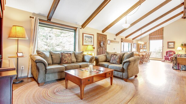 A spacious living room with a wooden coffee table, two sofas, and a large window providing natural light. - 3BR with Epic Mountain Views and Huge Deck! (Estes Park)