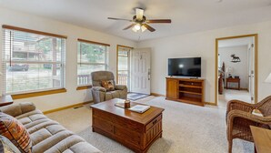 A spacious living room with a large television, comfortable seating, and a ceiling fan. - Conveniently located home w/ full kitchen, w/d, deck & mountain views (Estes Park)