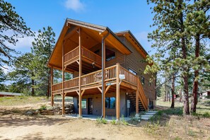 A wooden cabin with a balcony, a covered porch, and a staircase leading to the upper level. - Modern cabin with mountain views, private yard & furnished deck - great location (Estes Park)