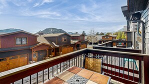 Zona residenziale con veranda in legno e vista su case e montagne.