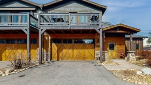 Una casa a due piani con facciata in legno, un balcone al piano superiore e un garage con cancello giallo.