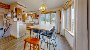 Tilava keittiö, jossa on suuri keittiösaareke, puulattia ja riippuvalaisin.