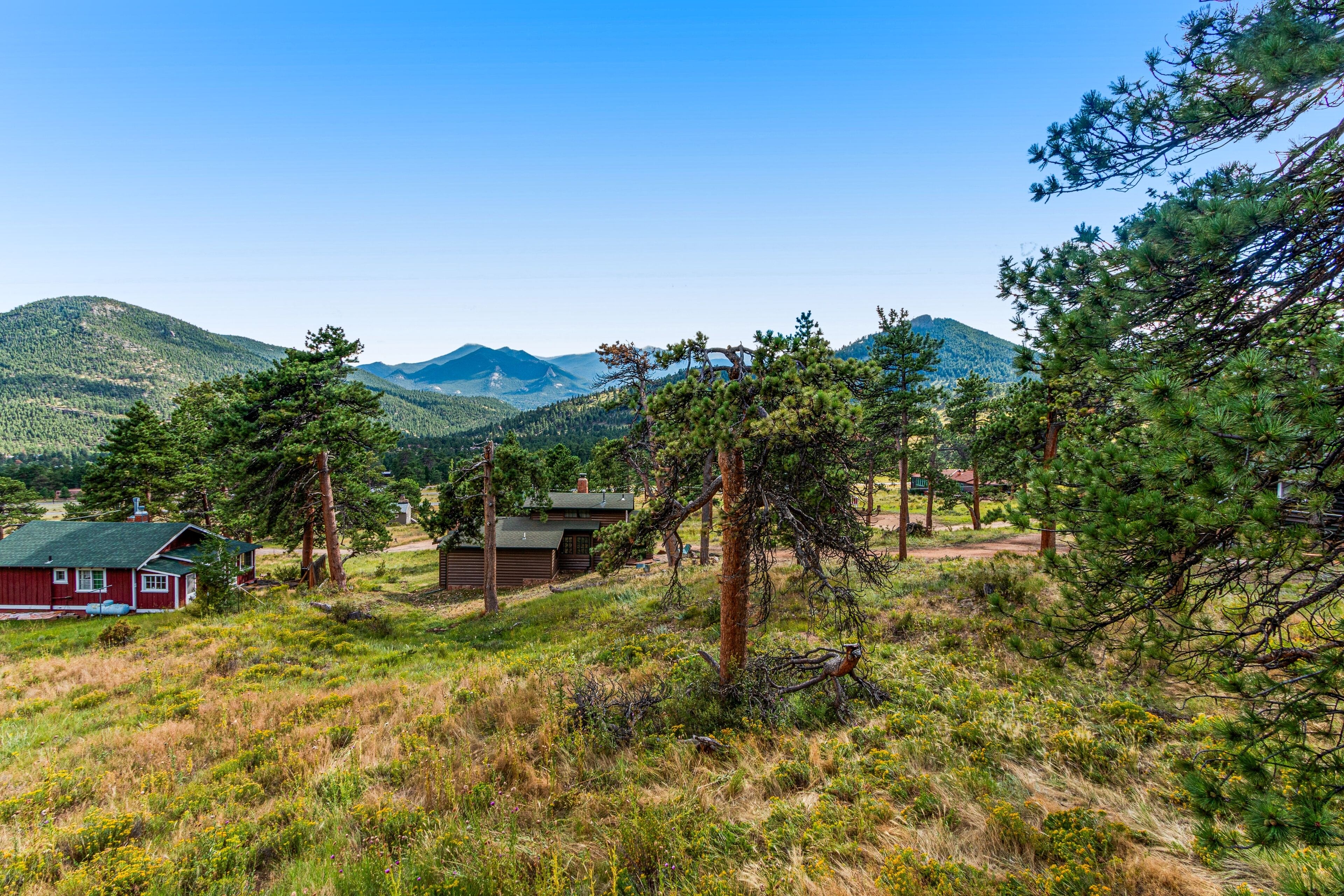 A cabin in a forested area with a clear view of mountains in the background.