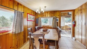 Ein Esszimmer mit Holzwandverkleidung, einem großen Tisch, Stühlen und einer Kristallleuchter.